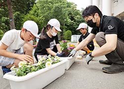 プランターに色とりどりの花苗を植える米沢小児童とJA職員