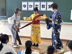 反物を広げて見せる着物を愛する会のメンバー