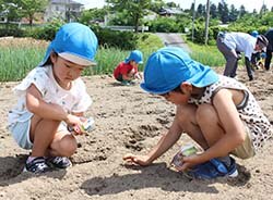 大豆の種まきをする園児