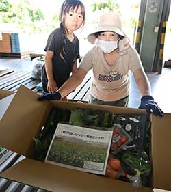 朝採りした野菜を手に取る部会員