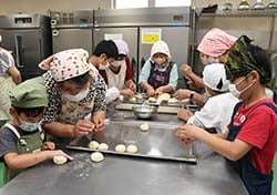 生地のまとめ方(丸め方)を伝える女性部員
