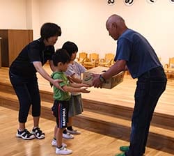 モモを園児に手渡す生産者