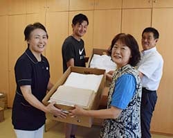 会員から集まったタオルを手渡す春日さん（右前）
