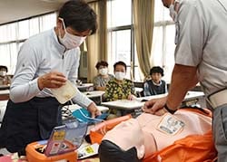 AEDを人形に貼り付ける参加者（左）