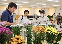 曾澤部長（左）から品種ごと説明を受ける来場者