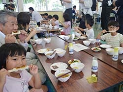 西村組合長（左奥）とともに五平餅を食べる児童