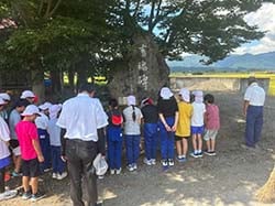 慰霊碑を前に黙とうする小学生と関係者ら