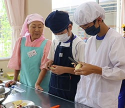 平沢さんに見守られながらりんごの皮をむく児童たち