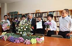 岡谷工業高校の生徒と管内産の花きやフラワーアレンジメントを眺める小平淳組合長（中）ら