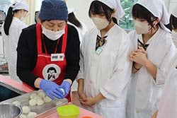 女性部員の指導で郷土料理を作る高校生