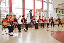 諏訪養護学校の子どもたちを前に笑顔でスコップ三味線を披露するメンバー