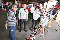 職員と会話を楽しみながら農機具を吟味する来場者。（19日、長野県松本市で）