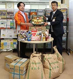 諏訪市福祉協議会の職員に食品を手渡す宮坂智明地区統括所長（右）