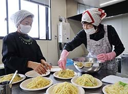 塩麹レモンパスタを皿に盛り付ける支部員