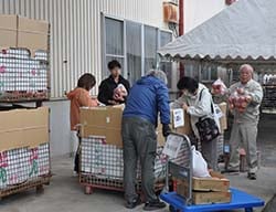 袋詰めりんごを吟味し購入する来場者ら