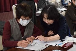 増田さん（右）に教わりながら、来年の干支「巳」を練習する参加者