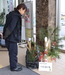 ナガイモ門松とヘビ長いもを笑顔で眺める来店者