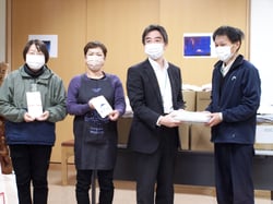 紅林荘の小林施設長（右）に清拭布を手渡す名取支所長ら