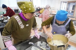 豆腐の固まりを鍋からざるに移す女性部員ら