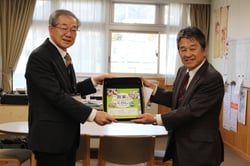 熊谷教育長（左）に教材本を贈呈した寺沢組合長（右）
