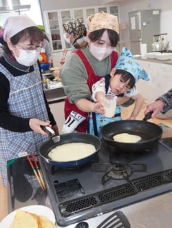 フライパンに米粉を流し入れる親子と女性部員（左）