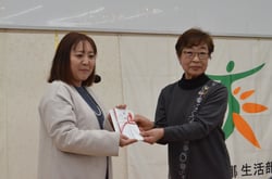 目録を手渡す山岸部会長（右）
