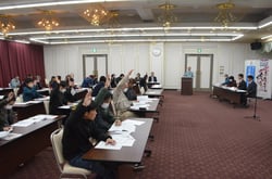 挙手にて議案が可決する様子