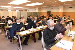 拍手で議案を承認する会場（長野県長野市、3月21日）