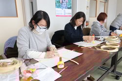 紙バンド同士を貼り付け作品を作り始める参加者