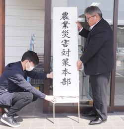 広域営農センターに看板を立て掛ける相馬常務（㊨）と営農職員