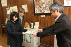 5学年の教諭2人に教材を手渡す小口和宏支所長