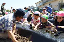 青年部員と定植作業を楽しむ園児ら