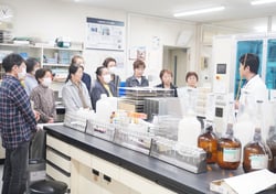 土壌検査を行う分析室を見学する女性部員ら