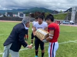 西村組合長（左）から米を受け取る代表選手