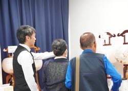 盆提灯の特徴を説明する担当者と来場者㊧