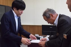 目録を天野村長（左）に手渡す田中理事（右）