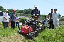無線操縦の草刈り機で土手の草を刈る参加者（１９日、長野県東筑摩郡麻績村にて）