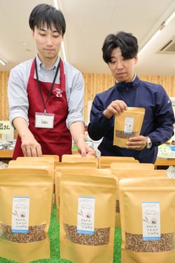 販売を開始した「たかきび（赤ソルガム）」を店内に並べる朝倉課長代理（右）と佐藤係長