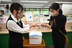 職員から冷たいおしぼりを受け取る来店者（右）