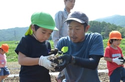 松田支部長（右）とポリポットから苗を取り出す園児