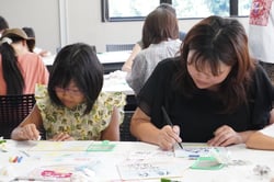 色紙に文字を書き入れたり色を塗る参加者