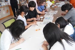 台紙にガラス材を張り付ける参加者たち