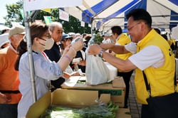 農産物販売コーナーで地元野菜を買い求める来場者