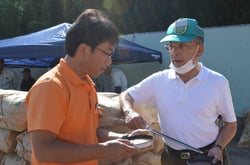 サンプル用の米を取り出して品質を確認する三浦技術審議役（右）とＪＡ職員