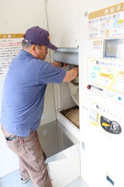 投入口に籾を入れる小池さん
