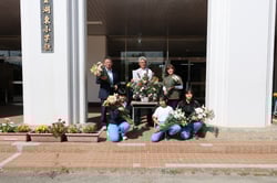 湖東小学校で児童へアレンジメントと花を渡す小平組合長（奥中央）