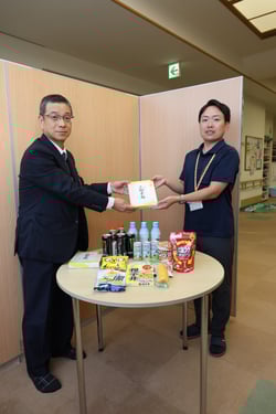 集まった食品を手渡す宮坂統括所長（左）