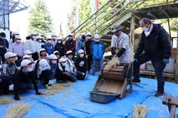 脱穀の説明を聞く児童