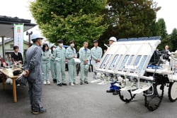 デモンストレーションで機械の使用方法をきく生徒ら