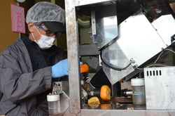 皮むき機に柿を置く作業員